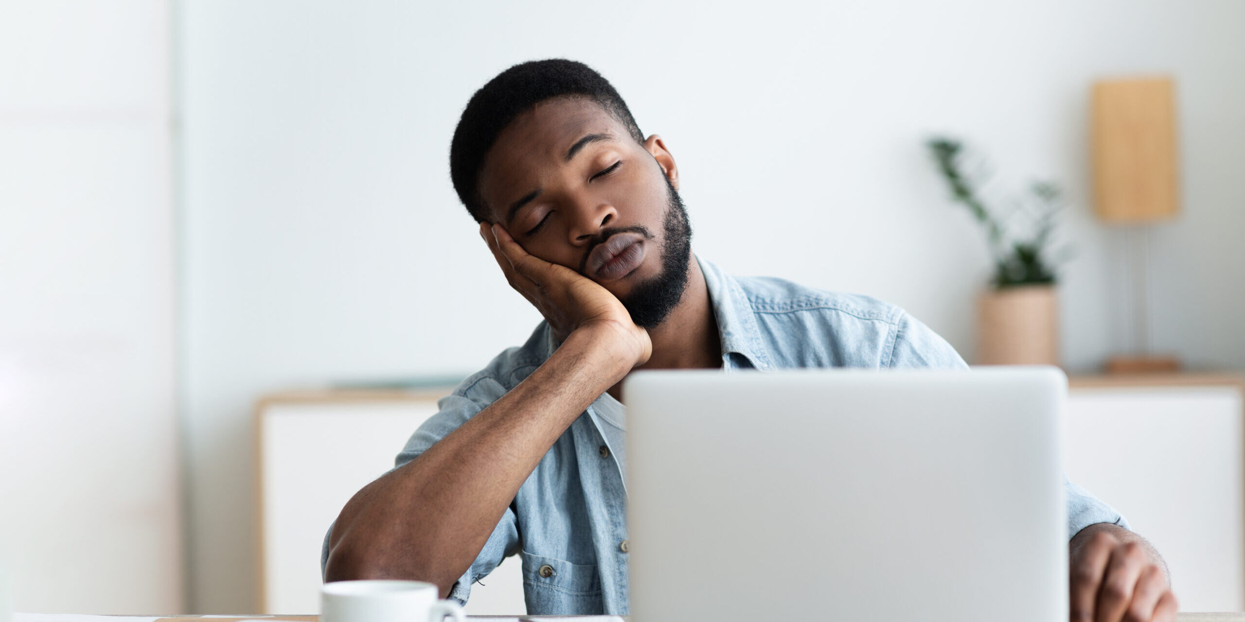 Exhausted African American worker felt asleep at workplace, panorama with copy space